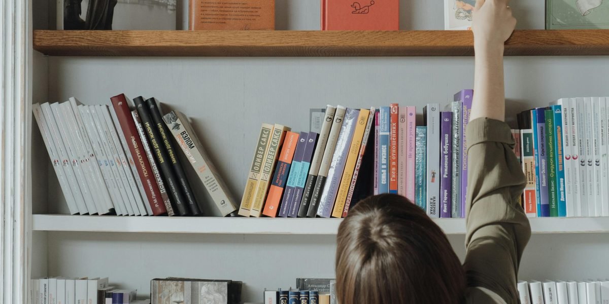 A person browsing a large collection of books, contemplating their next read.