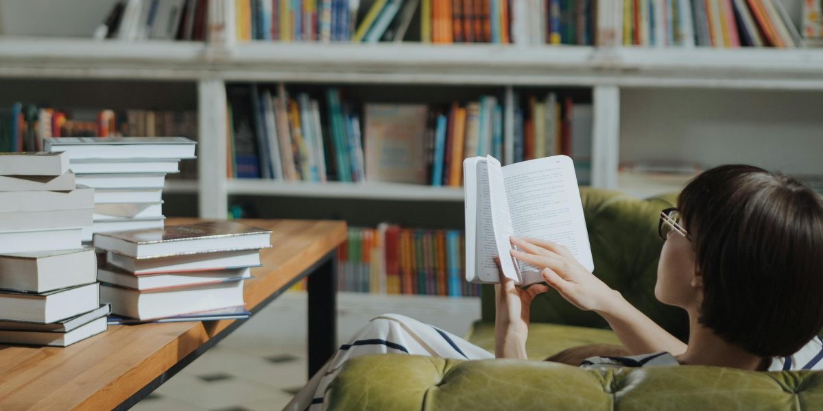 A person contemplating a stack of books, searching for their next captivating read.